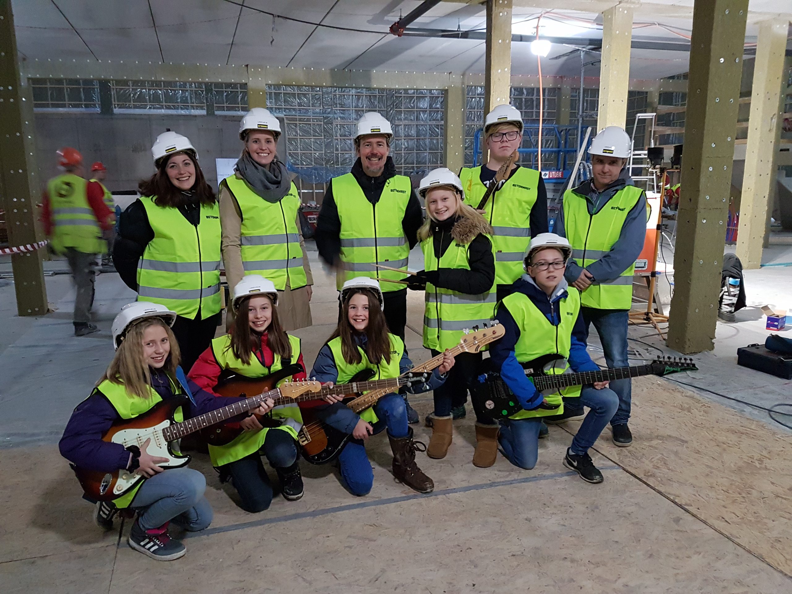 En gjeng i refleksvest og hjelm, noen med gitarer