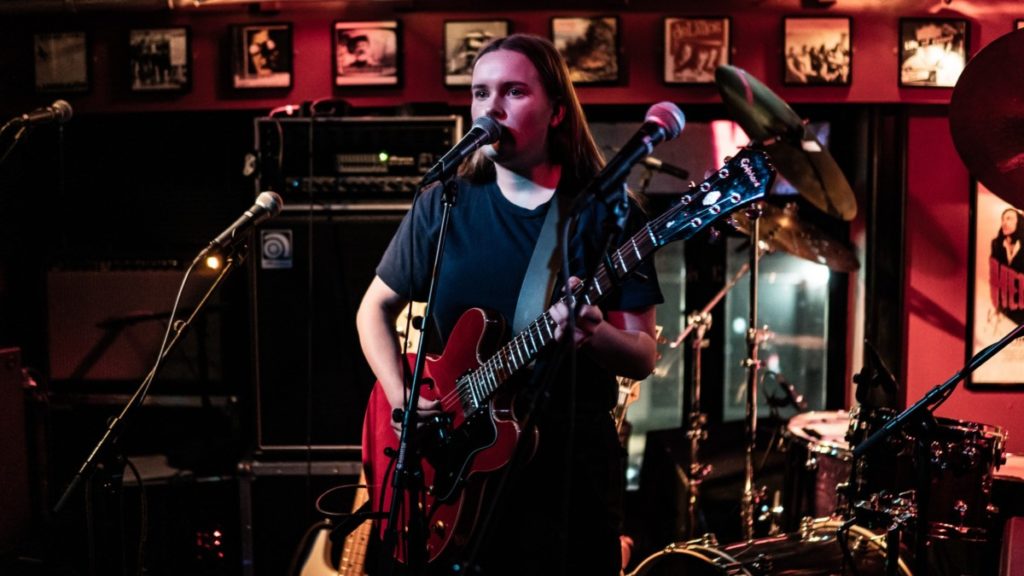 En kvinne spiller gitar og synger
