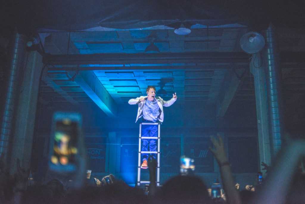 En musiker synger til publikum på toppen av en stige